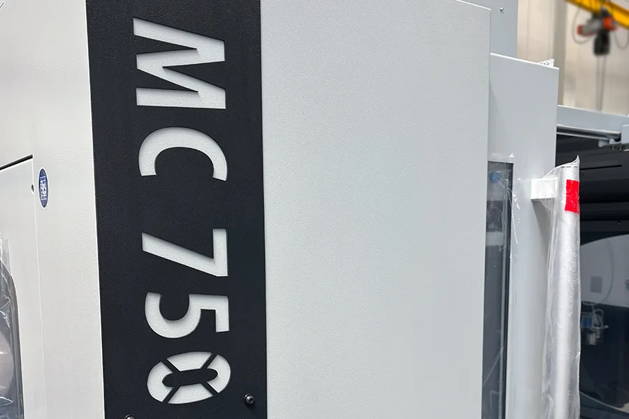 Detail of MC 750 CNC milling machine showing model designation and robust housing construction Detail CNC frézky MC 750 s označením modelu a robustnou konštrukciou skrine